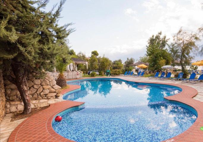 a swimming pool in a resort with blue water at vassilias beach hotel in Vassilias