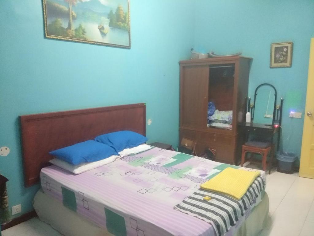 een slaapkamer met een bed met blauwe muren en een dressoir bij Seri Lagenda Apartment in Kuah