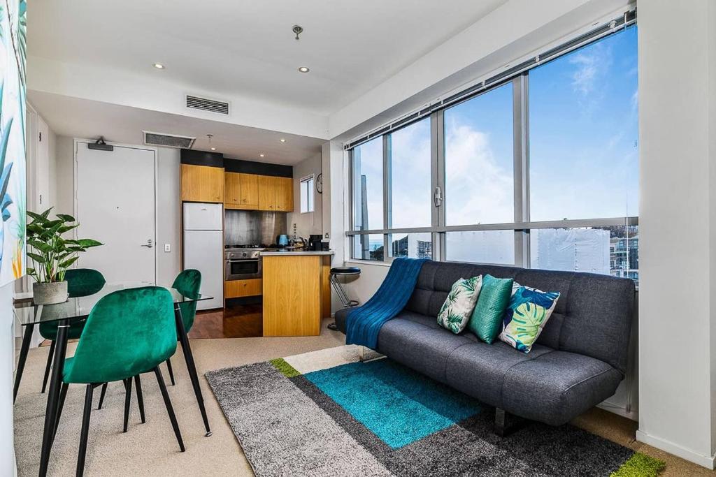 a living room with a couch and a kitchen at One Bedroom Apartment - Pool, Gym & Tennis Courts! in Auckland