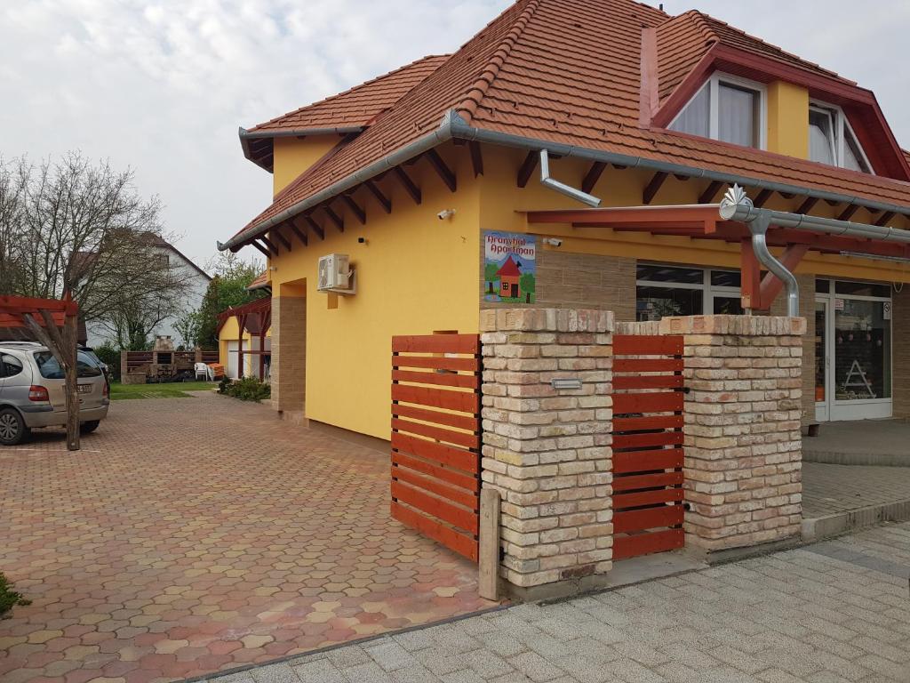 una pequeña casa con una valla roja delante de ella en Aranyhal Apartman, en Hévíz