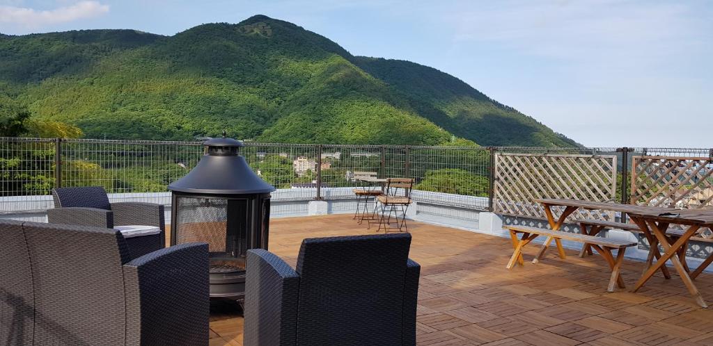 eine Terrasse mit einem Tisch, Stühlen und einem Berg in der Unterkunft Hakone Guest House gaku. in Hakone