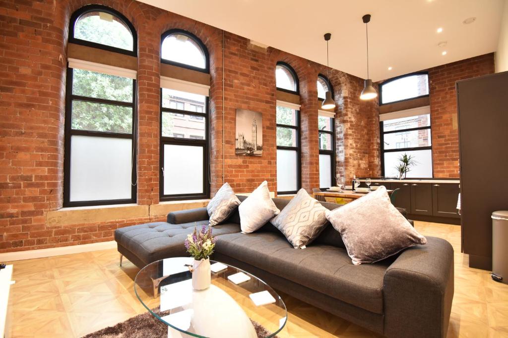 a living room with a couch and a brick wall at Aire Apartments New York Styled Luxury Apartments in Leeds