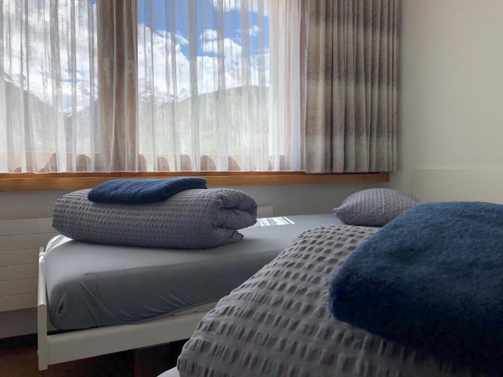 a bedroom with a bed with pillows and a window at Catrina Lodge in Disentis
