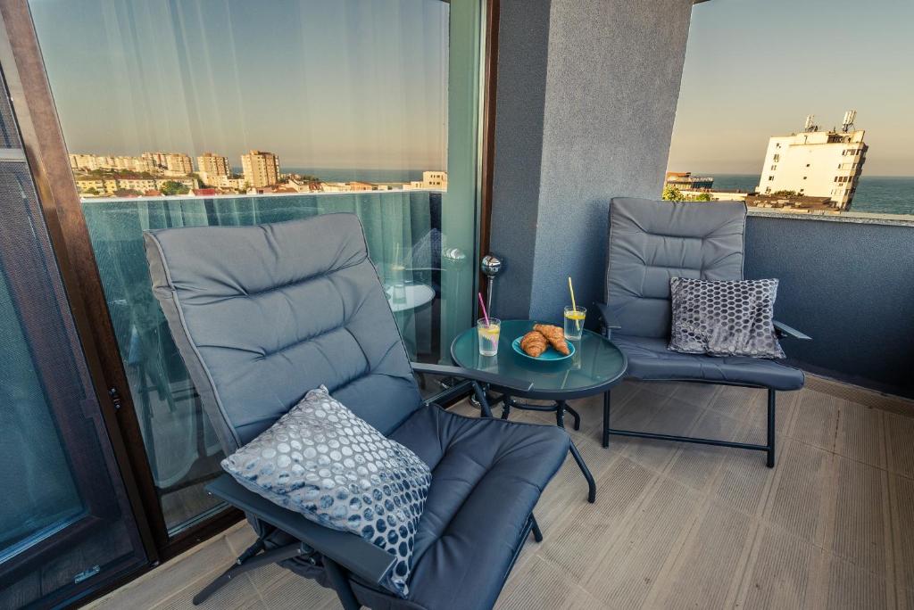 uma varanda com 2 cadeiras e uma mesa de vidro em Luna Apartment em Constança