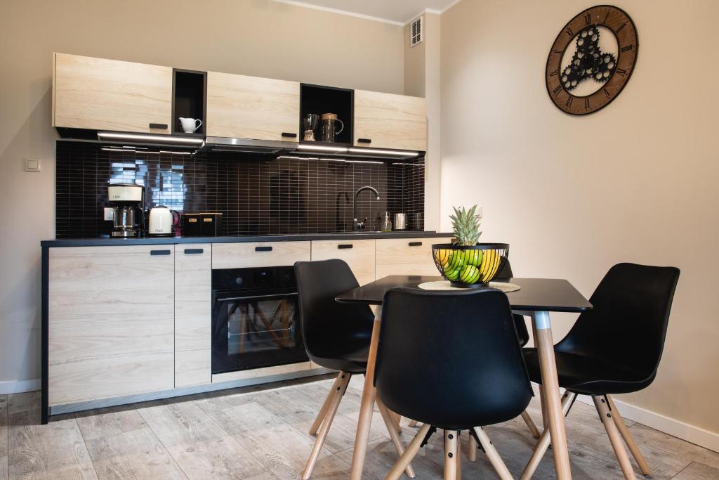 een keuken met zwarte stoelen en een tafel en een klok bij Apartamenty Silence Baltic Classic in Pobierowo