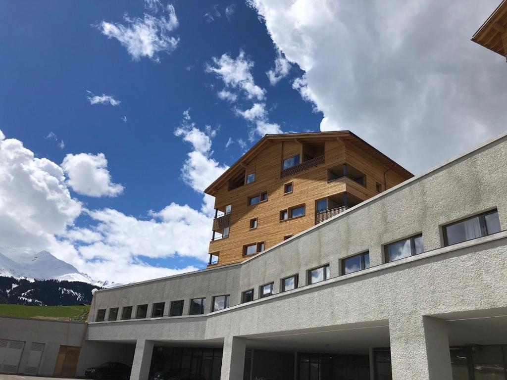 a building with a wooden building on top of it at Catrina Hostel in Disentis