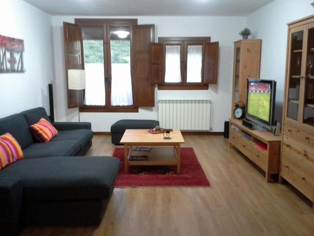 sala de estar con sofá, mesa y TV en APARTAMENTO FONTELLAS-AYERBE, en Fontellas