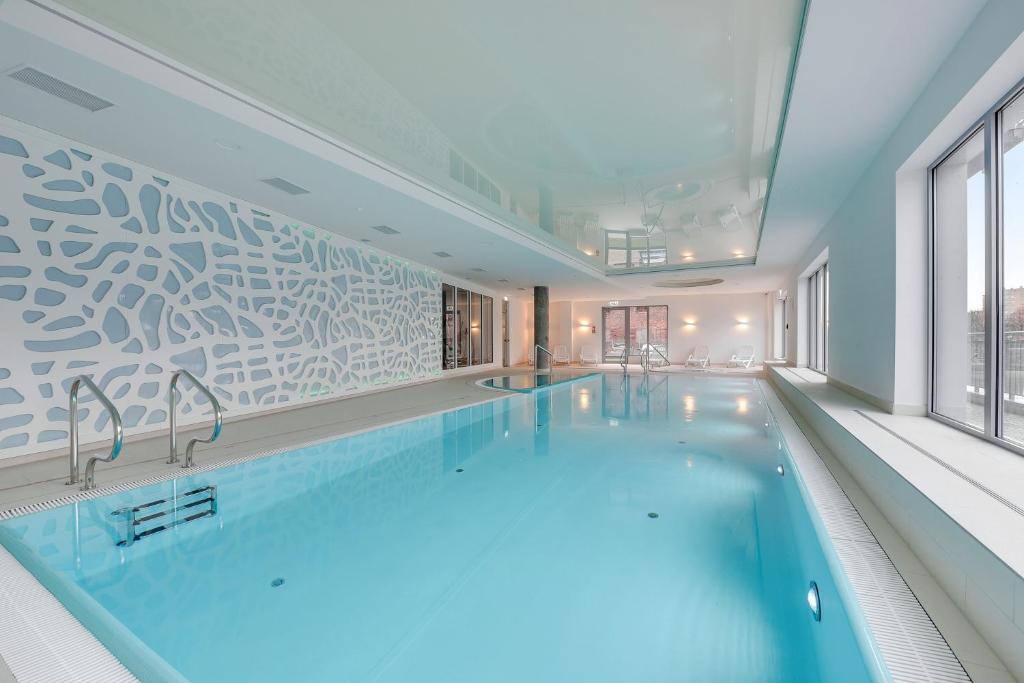 a large swimming pool in a building at Downtown Apartments Waterlane Island -Riverview Pool, SPA, Gym & Parking in Gdańsk
