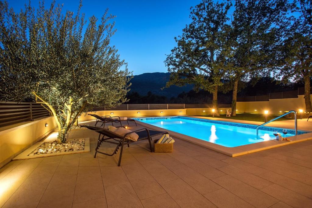 - une piscine dans un jardin la nuit dans l'établissement VILLA SKURA private heated pool 32m2, summer kitchen, 4 bedrooms, garden, à Duće