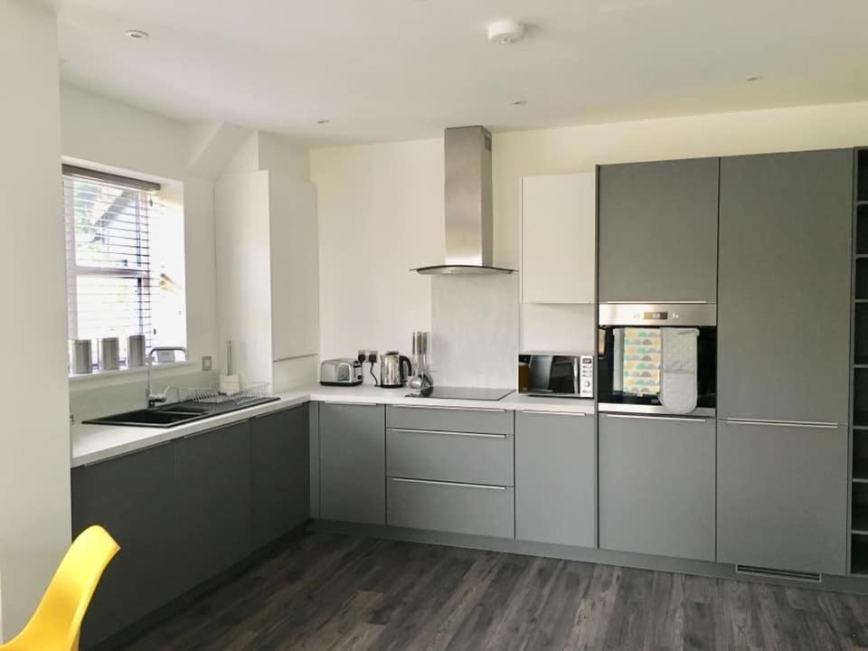 una cocina con armarios blancos y una silla amarilla. en Impressive newly built apartment, en Conwy