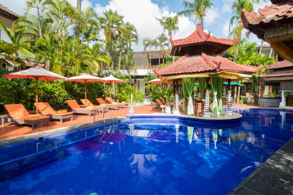 a pool at a resort with chairs and umbrellas at Sarinande Hotel in Seminyak