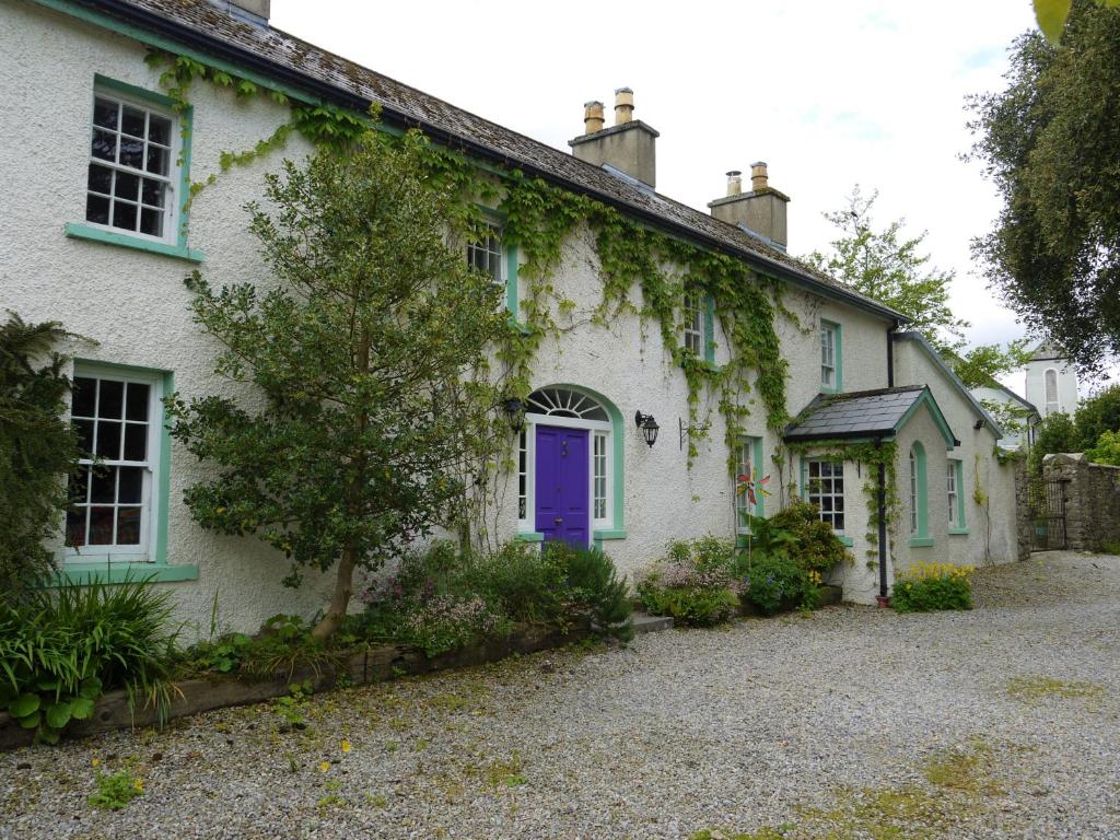 a white house with a purple door at The Coachhouse @ Kingsfort House in Ballintogher