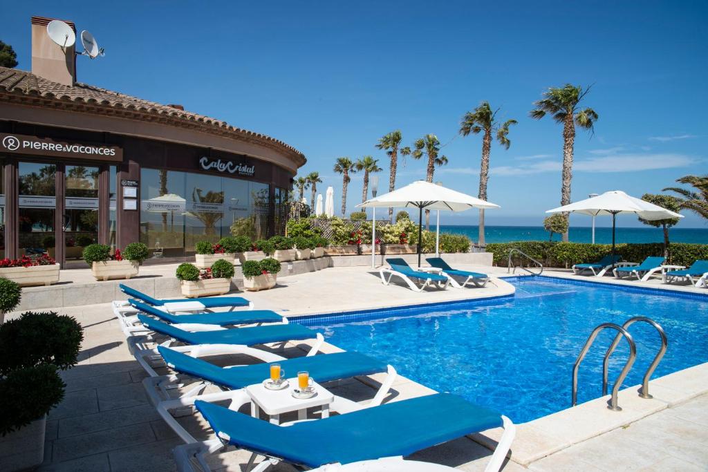 a pool with chairs and umbrellas at a resort at Cala Cristal by Pierre & Vacances Premium in Miami Platja