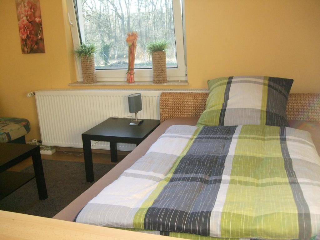 a bedroom with a bed with a table and a window at PP. Pension Petra in Neuenkirchen-Vörden