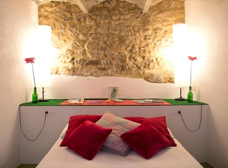 - un lit avec 2 oreillers rouges et un mur en pierre dans l'établissement Ca la Teia, à Bellcaire dʼEmpordà