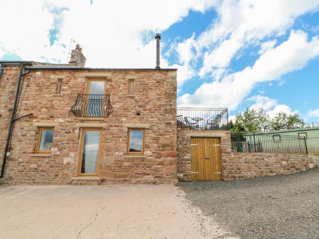 a brick house with a balcony on top of it at Apple Tree Cottage in Soulby