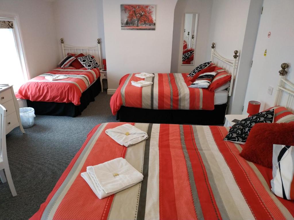 a room with three beds with red and striped sheets at The Castleton in Blackpool