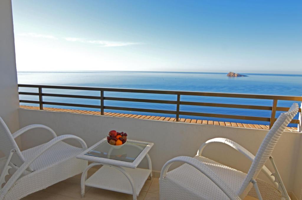 Un balcón con sillas y una mesa con vistas al océano. en Les Dunes Comodoro en Benidorm