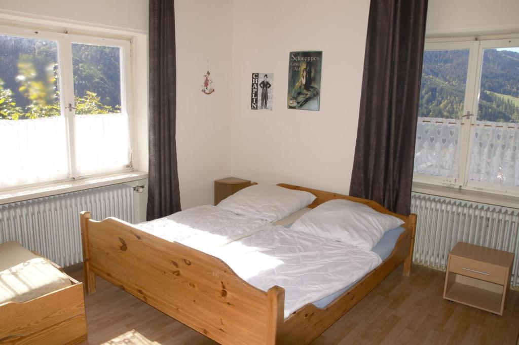 a bedroom with a wooden bed with two windows at Berg & Skihütte -Schmittenhof in Laterns