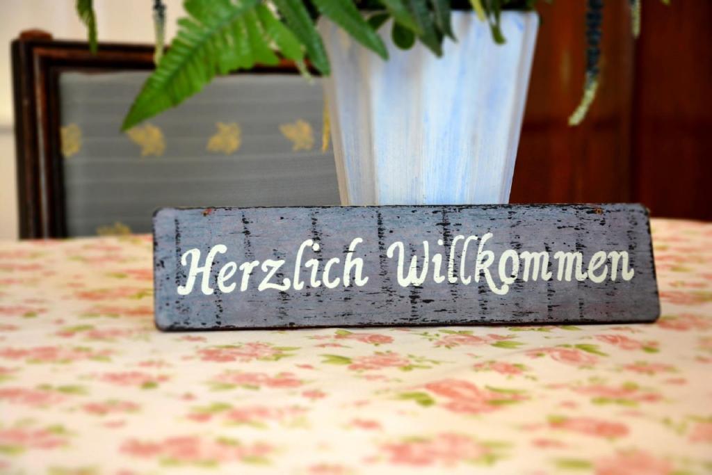 ein Schild auf einem Tisch mit einer Vase in der Unterkunft Gasthaus & Gästehaus Bsteh in Wulzeshofen