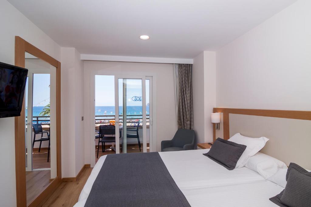 a hotel room with a bed and a view of the ocean at Les Dunes Comodoro in Benidorm