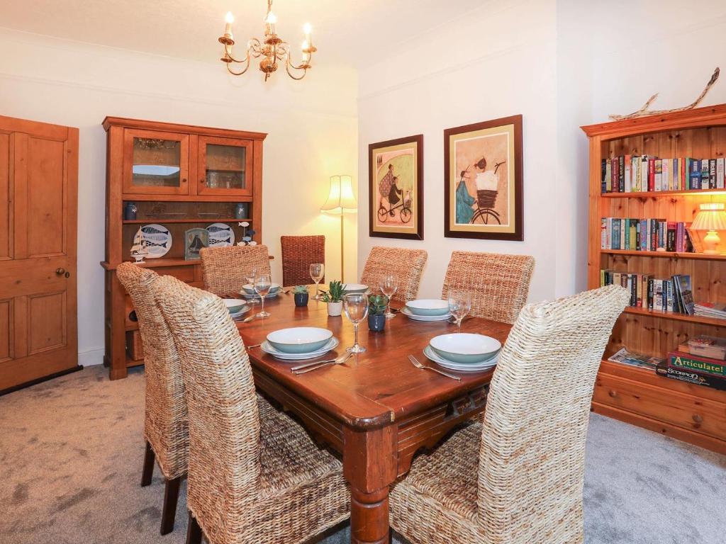 uma sala de jantar com uma mesa de madeira e cadeiras em Swn Y Mor em Criccieth