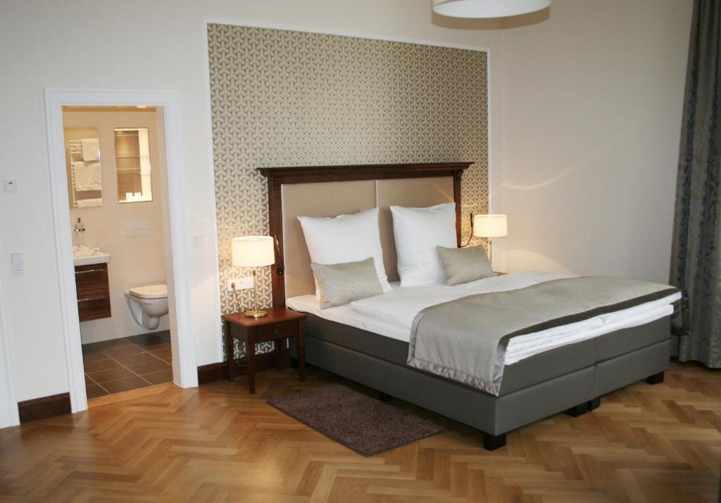 a bedroom with a bed with two lamps and a bathroom at Hotel Villa Altenburg in Pößneck