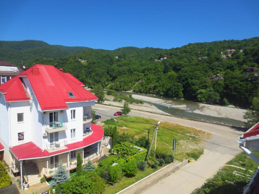 een huis met een rood dak en een rivier bij Mishel House in Lazarevskoje