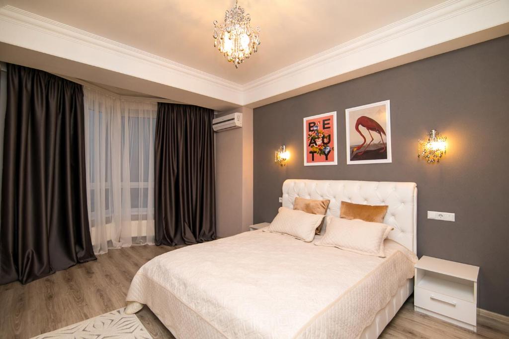 um quarto com uma cama branca e um lustre em Rightmove Apartments em Chisinau