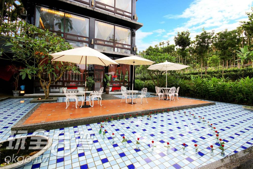 a pool with tables and chairs and umbrellas at Full House Homestay in Yuchi