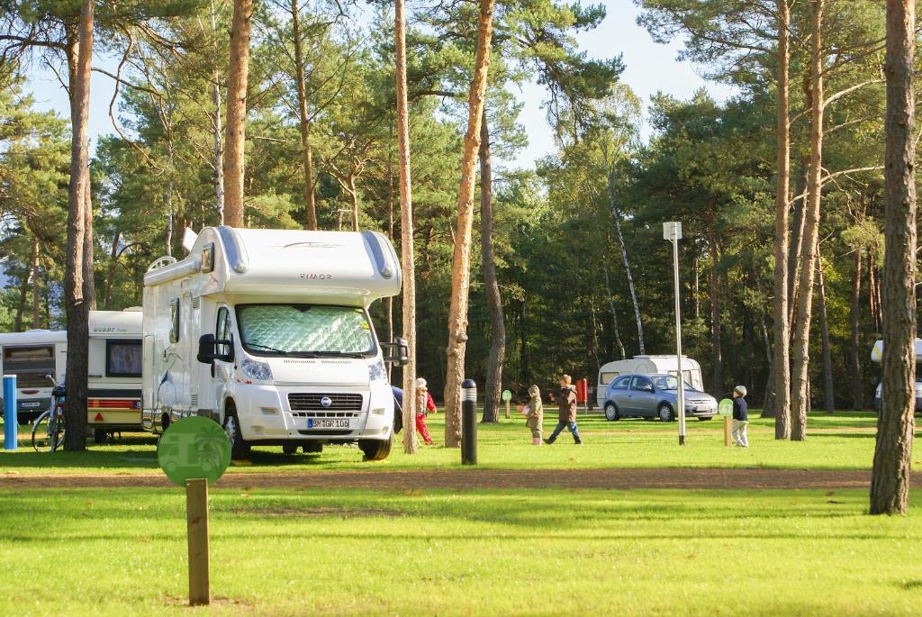 biała ciężarówka zaparkowana w parku z chodzącymi ludźmi w obiekcie Tropical Islands Campingplatz w mieście Krausnick