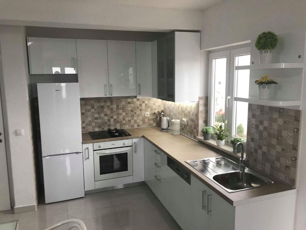 Una cocina blanca con gabinetes blancos y un fregadero. en Apartments Jure, en Makarska