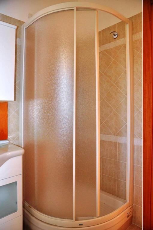 W łazience znajduje się prysznic ze szklanymi drzwiami. w obiekcie Villa Smeraldo Roma w mieście Infernetto