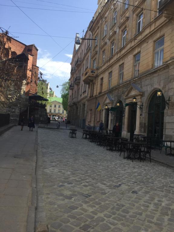 a cobblestone street in a city with tables and buildings at Heart of Lviv in Lviv
