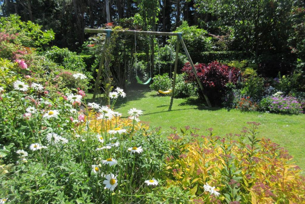 un jardin avec une balançoire et des fleurs dans l'établissement Le Seringat, à Saint-Léonard