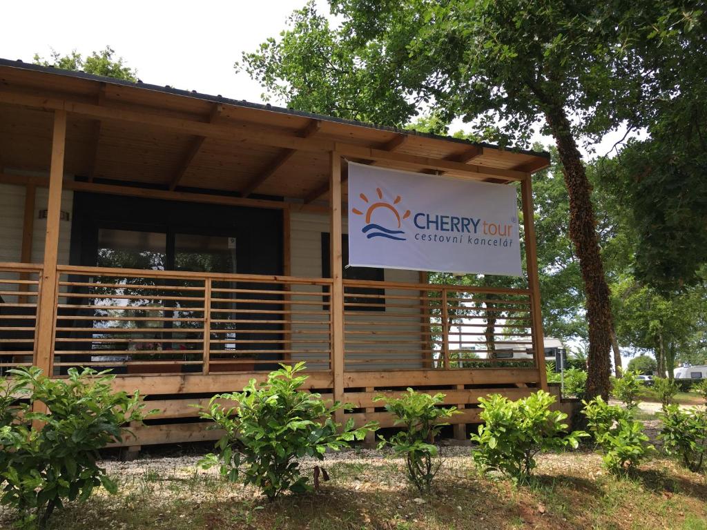 ein Gebäude mit einem Schild für ein fröhliches Gartenzimmer in der Unterkunft CHERRY Premium ADRIA Mobile homes Zelena Laguna in Poreč