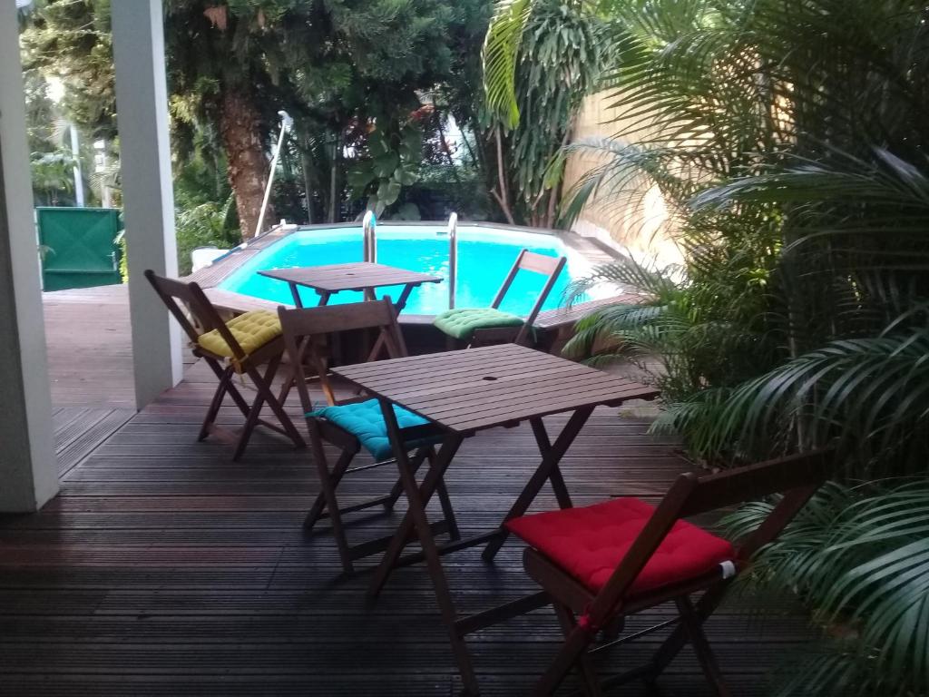a patio with tables and chairs in front of a pool at Le Frangipanier Villa avec piscine in Saint-Denis