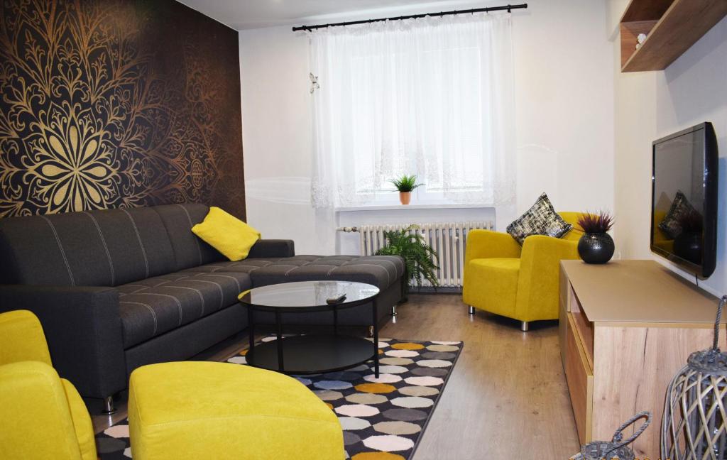 a living room with a couch and yellow chairs at City Center Apartment II in Nitra