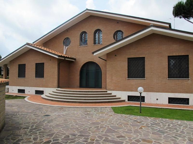 duży ceglany budynek ze schodami i drzwiami w obiekcie Villa Smeraldo Roma w mieście Infernetto