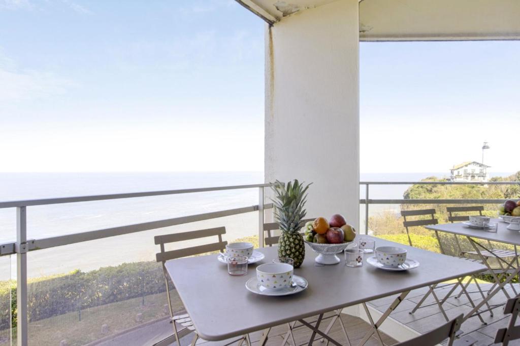 a table with a bowl of fruit and a view of the ocean at Bright T2 with balcony and sea view in Biarritz in Biarritz