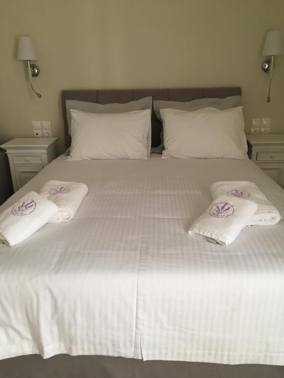 a white bed with two white towels on it at LEVANTA HOTEL SPETSES in Spetses
