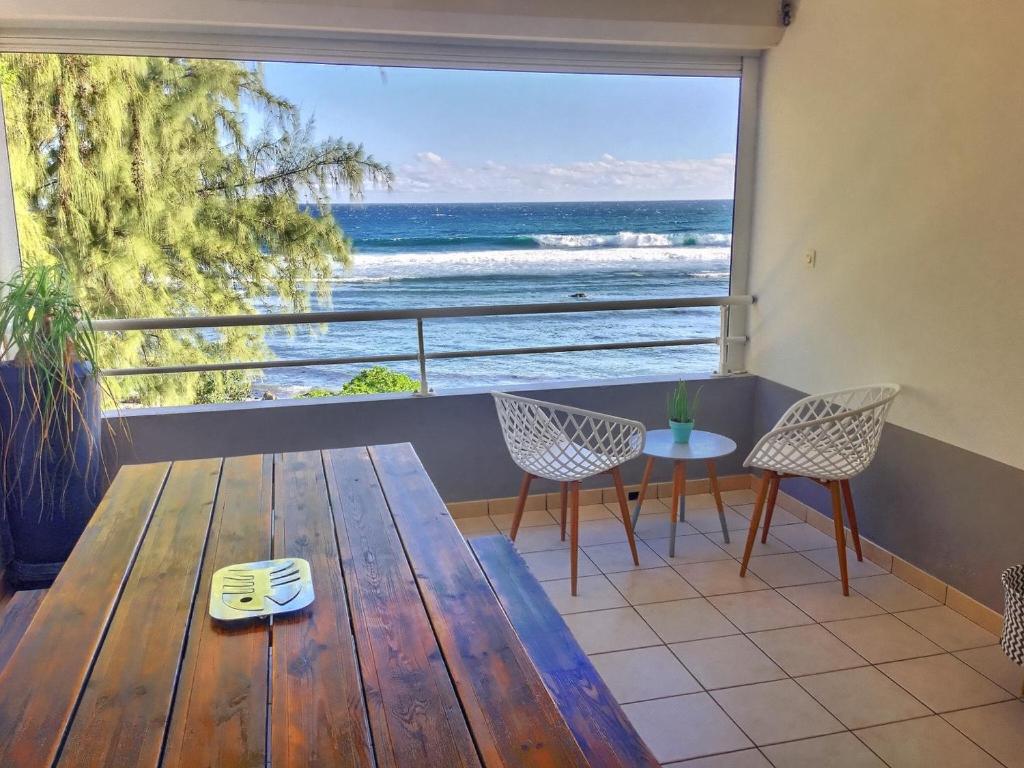 - une table en bois avec des chaises et une vue sur l'océan dans l'établissement duplex sur la plage, à Saint-Leu