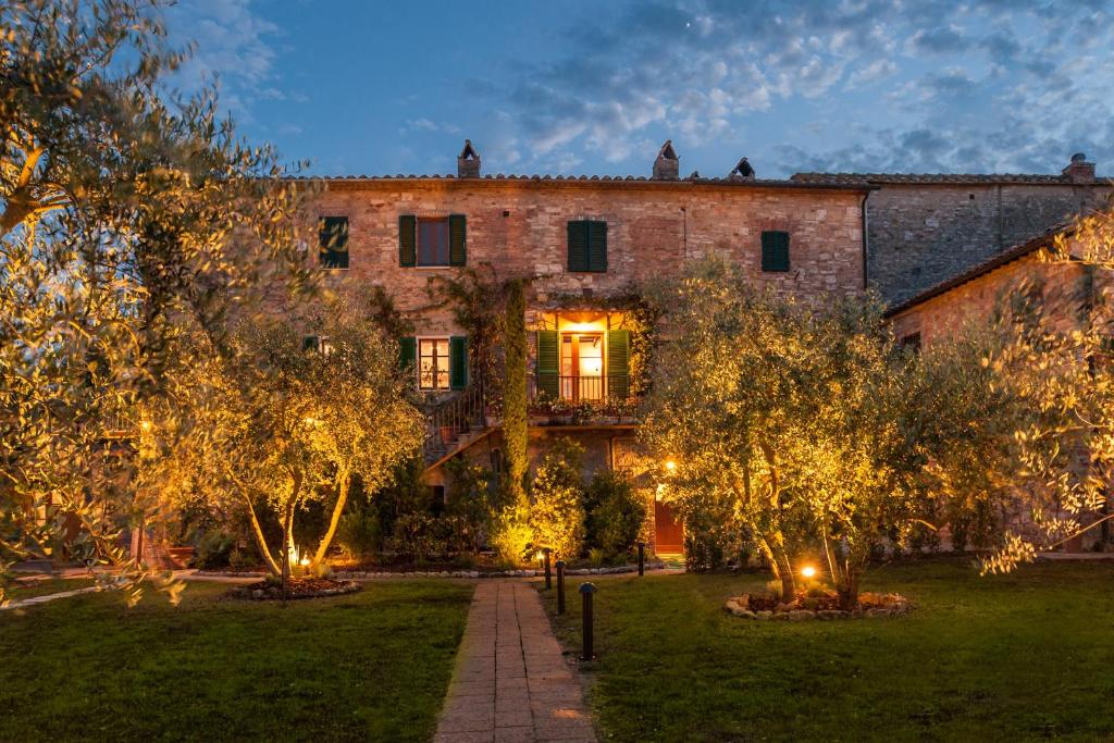 a large brick building with trees in front of it at B&B L'orto Delle Terme in Bagno Vignoni