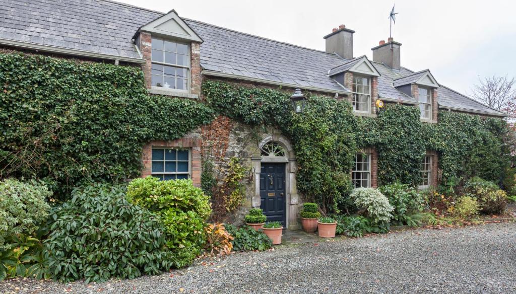 an ivy covered house with a black door at Collon House in Collon