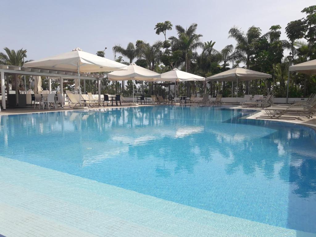 a large blue swimming pool with umbrellas and chairs at La Casa Di Napa Apartments in Ayia Napa