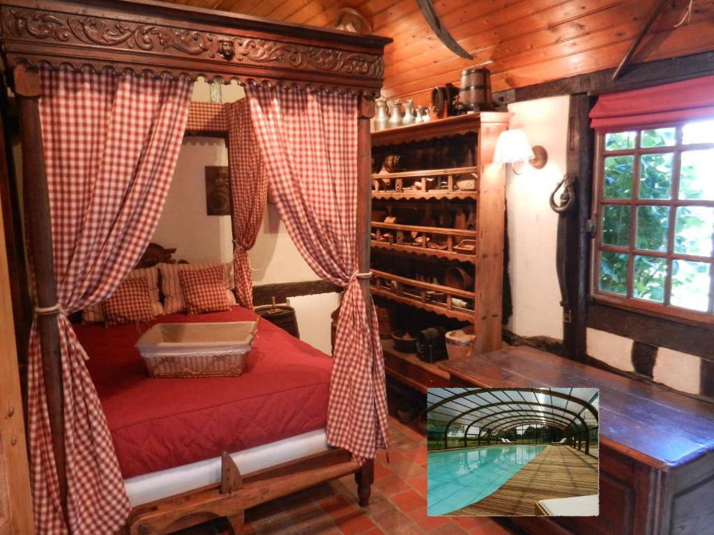 a room with a canopy bed with a glass table at Le gîte des Trois Vaches in Brionne