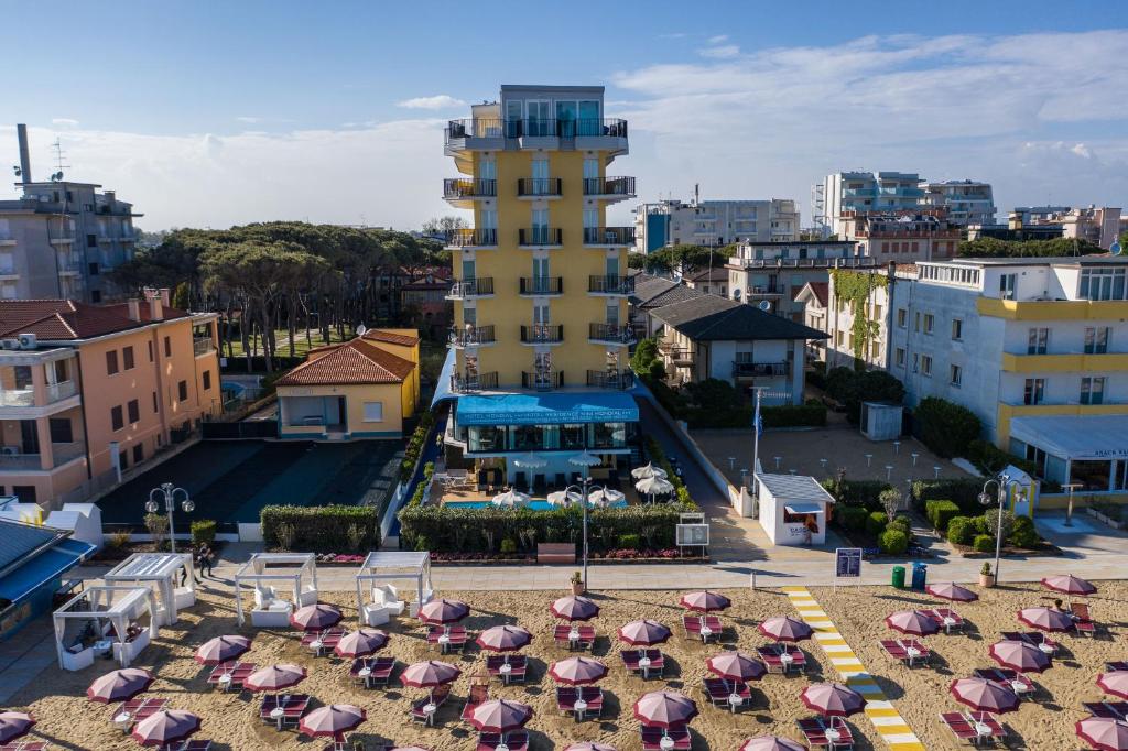 eine Gruppe von Sonnenschirmen am Strand mit einem Gebäude in der Unterkunft Hotel Mondial in Lido di Jesolo