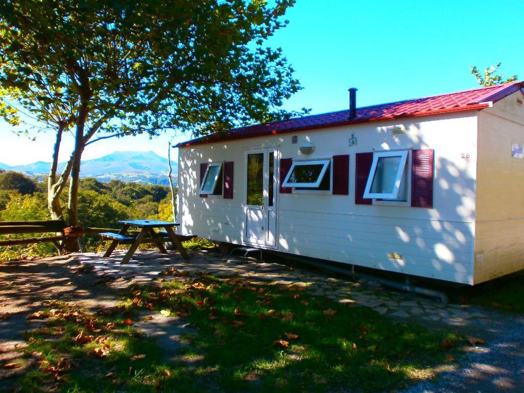 un remolque blanco con una mesa de picnic al lado en camping Manex, en Saint-Pée-sur-Nivelle