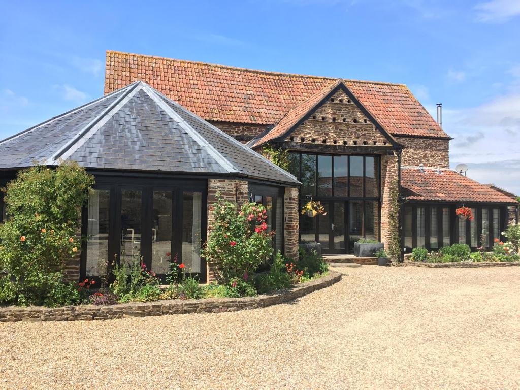 a brick building with windows and flowers in a yard at Bagstone Court Barn in Rangeworthy