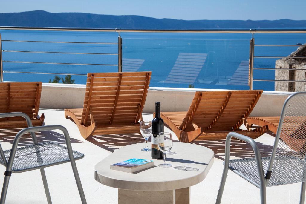 a patio with two chairs and a table with wine glasses at VILLA FENIX PODGORA in Podgora